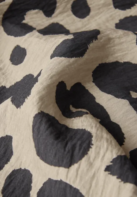 Beiger Stoff mit schwarzem Leopardenmuster.